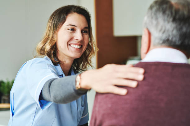 A female nurse patting an older man on the back